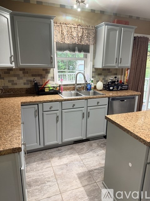 A kitchen with granite countertops and grey cabinets.