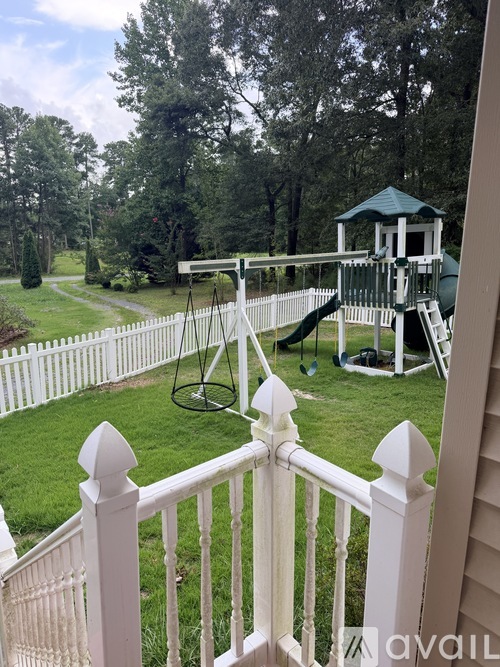 A white fence with a playground in the background.