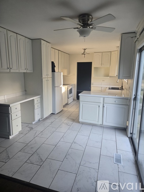 A kitchen with white cabinets and a ceiling fan.
