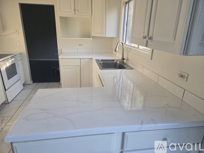 A kitchen with white cabinets and a black refrigerator.