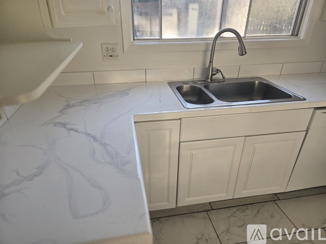 A kitchen with a marble countertop and a stainless steel sink.