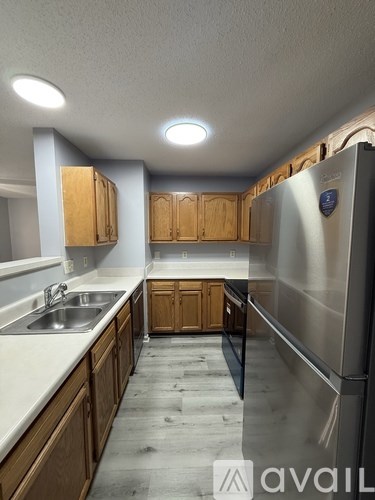 A kitchen with wooden cabinets and a stainless steel refrigerator.