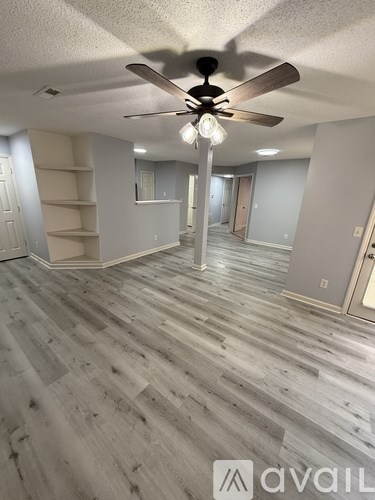 A room with a ceiling fan and wooden flooring.