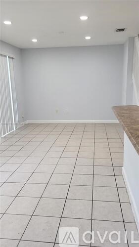 A spacious room with white walls and a tiled floor.