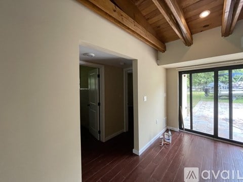 A room with wooden ceiling and floor with a doorway leading to another room.