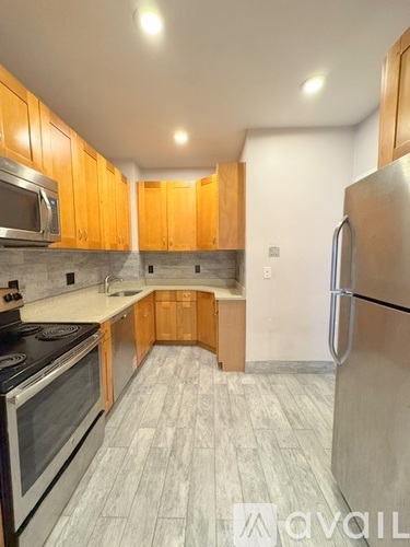A kitchen with wooden cabinets and a stainless steel refrigerator.