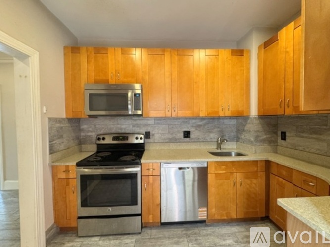 A kitchen with wooden cabinets and a stainless steel dishwasher.