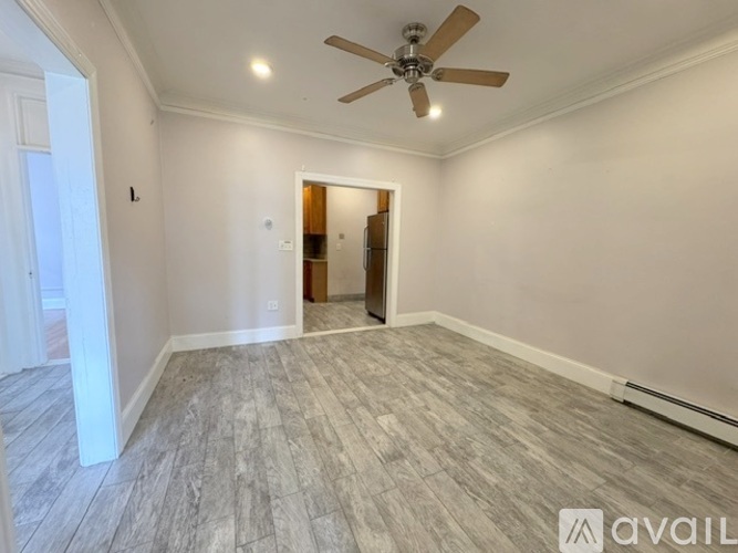 A room with a ceiling fan and lighting fixture, and a doorway leading to another room.