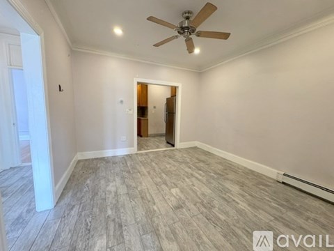 A room with a ceiling fan and lighting fixture, and a doorway leading to another room.