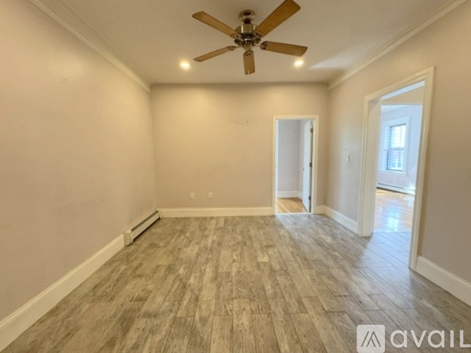 A room with a ceiling fan and lighting fixture, and a wooden floor.