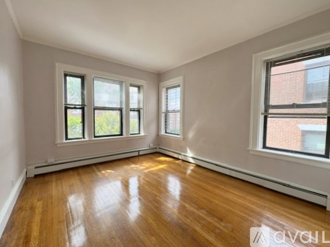 Empty room with wooden floors and three windows.