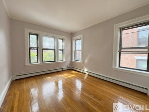 Empty room with wooden floors and three windows.