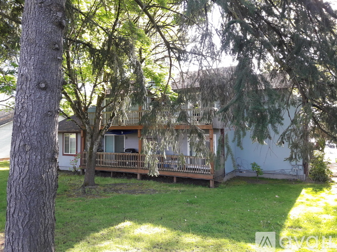 A house with a porch and a tree in front.