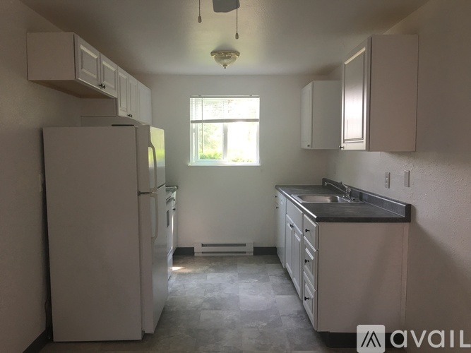 A kitchen with white appliances and cabinets is available for rent.