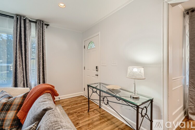 A living room with a glass coffee table and a lamp on it.