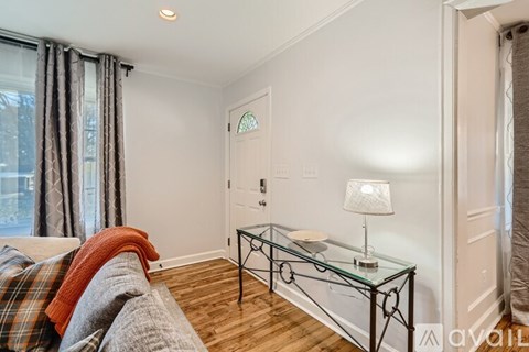 A living room with a glass coffee table and a lamp on it.