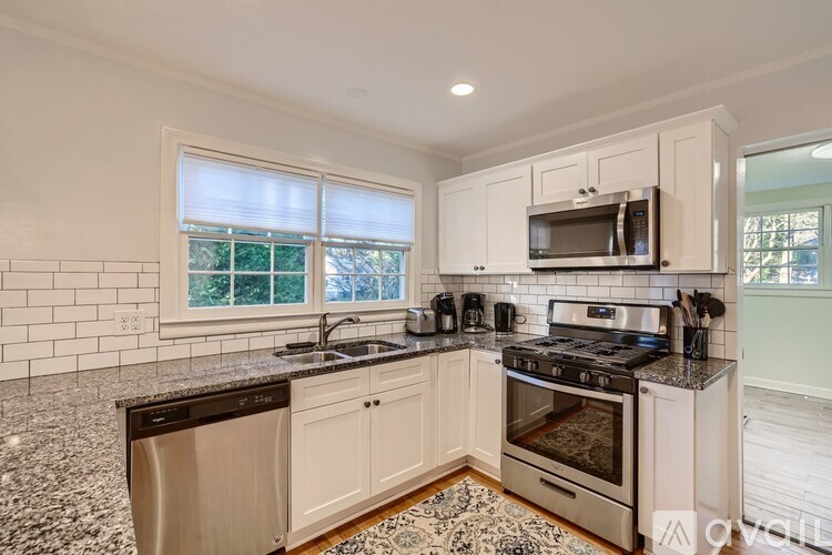A kitchen with white cabinets and black countertops.