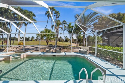 A pool with a white fence and trees in the background.