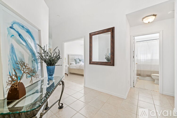 A living room with a glass table and a painting on the wall.
