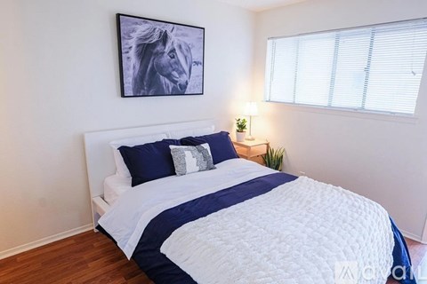 A bedroom with a white bed and a blue and white striped comforter.