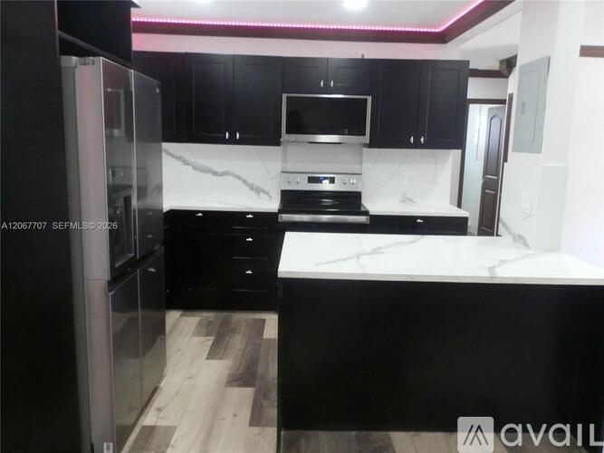 A modern kitchen with black cabinets and a marble countertop.