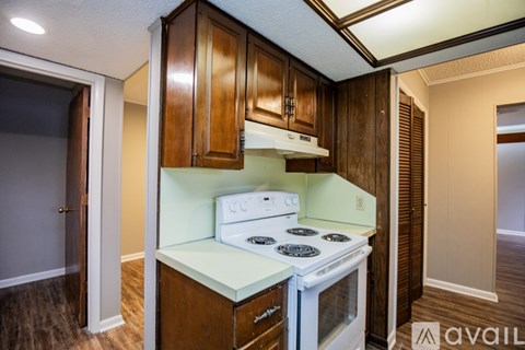 A kitchen with a white stove top oven and wooden cabinets.