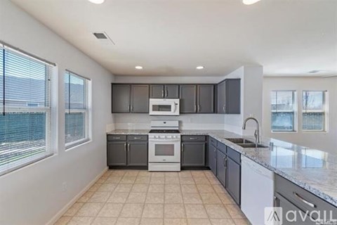 A kitchen with a white stove top oven and a white dishwasher.
