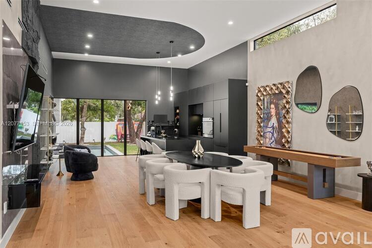 A modern dining room with a black table and white chairs.