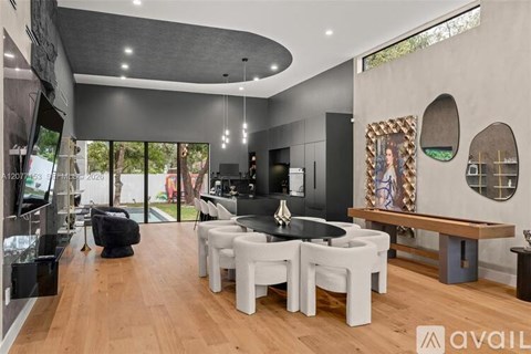 A modern dining room with a black table and white chairs.