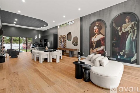 A living room with a white couch and a painting of a man in a red coat.