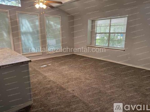 A room with a ceiling fan, carpeted floor, and a window with blinds.