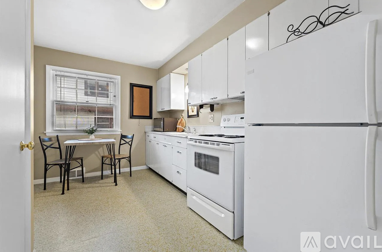 A kitchen with white appliances and a dining table with chairs.