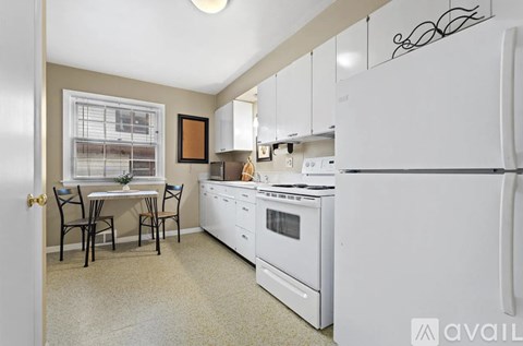 A kitchen with white appliances and a dining table with chairs.