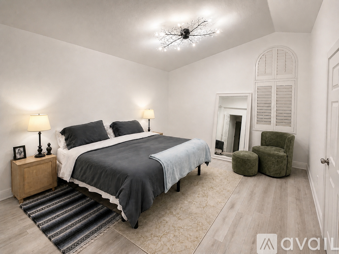A bedroom with a large bed and a green chair.