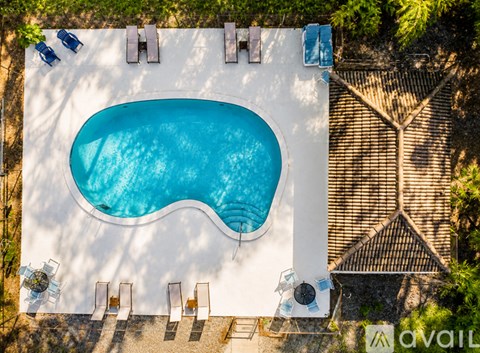 An aerial view of a swimming pool surrounded by a white wall and lounge chairs.