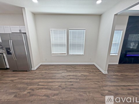A kitchen with a refrigerator and wooden flooring.