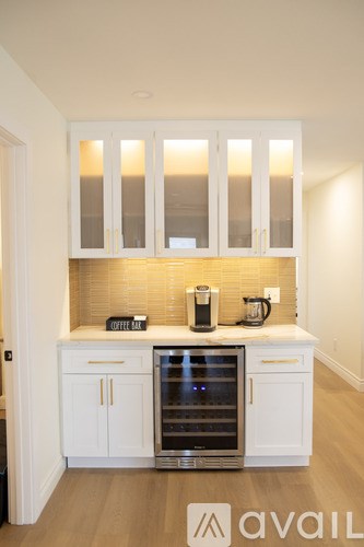 A kitchen with white cabinets and a wine cooler.