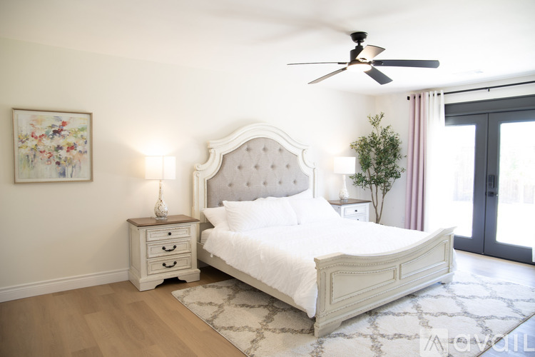 A white bedroom with a large bed and a ceiling fan.