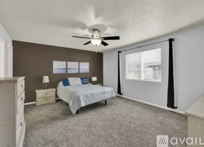 A bedroom with a bed, dresser, and window with blinds.