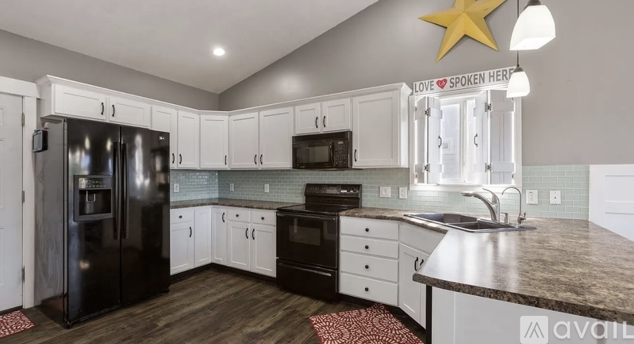 A kitchen with a black refrigerator, white cabinets, and a star decoration on the ceiling.