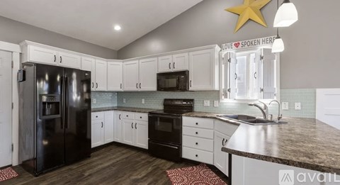 A kitchen with a black refrigerator, white cabinets, and a star decoration on the ceiling.
