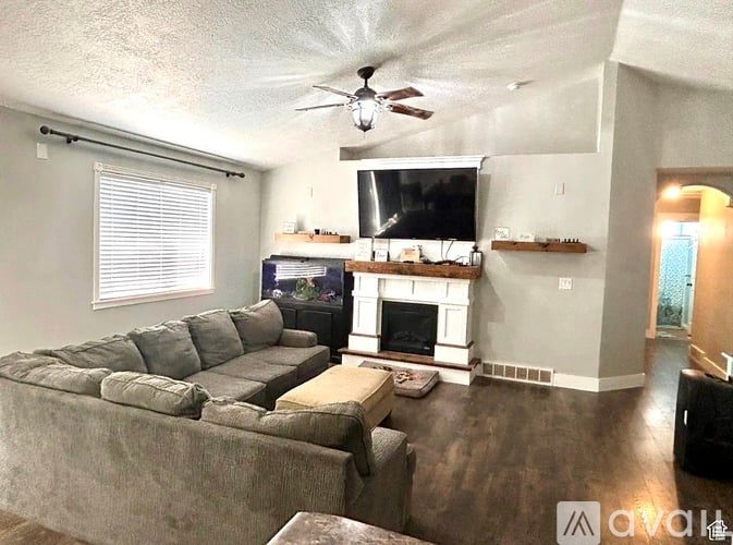A living room with a grey couch and a fireplace.