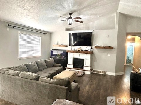 A living room with a grey couch and a fireplace.