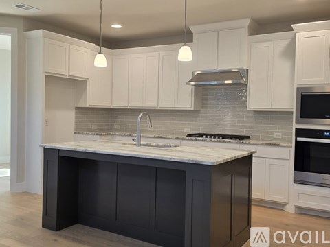 A modern kitchen with a large island and stainless steel appliances.