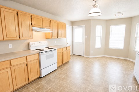 A kitchen with wooden cabinets and a white stove top oven.