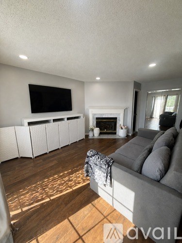 A living room with a grey couch and a fireplace.