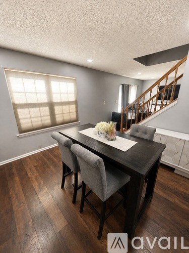 A dining room with a table set for two and a staircase in the background.