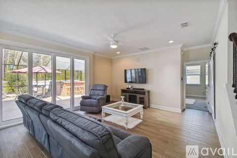 A living room with a grey couch and a television on the wall.