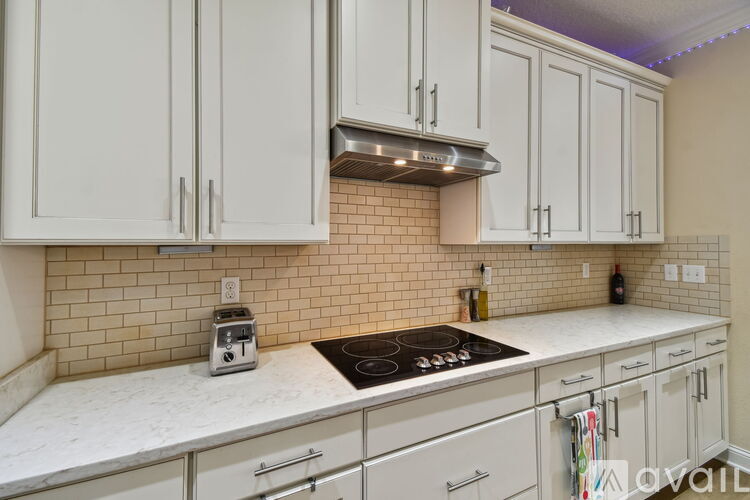 A kitchen with white cabinets and a tiled backsplash.