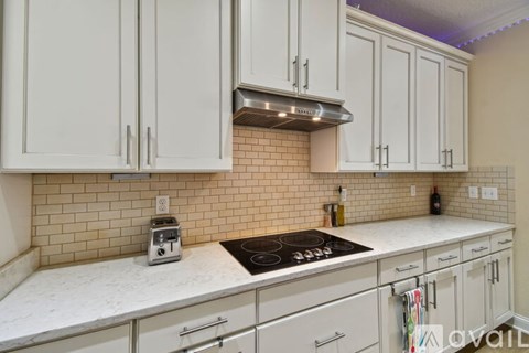 A kitchen with white cabinets and a tiled backsplash.